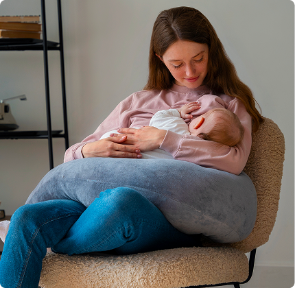Mother feeding baby on the couch using Sipee Sip feeding pillow