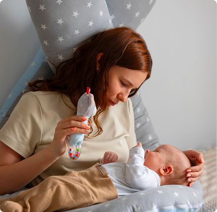 Mother bottle feeding baby during a late-night feeding with Sipee Sip pillow