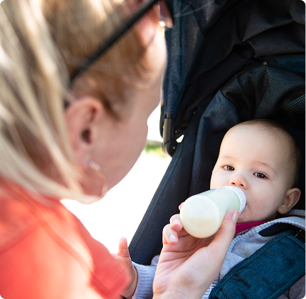Baby bottle feeding hands-free in a stroller while traveling